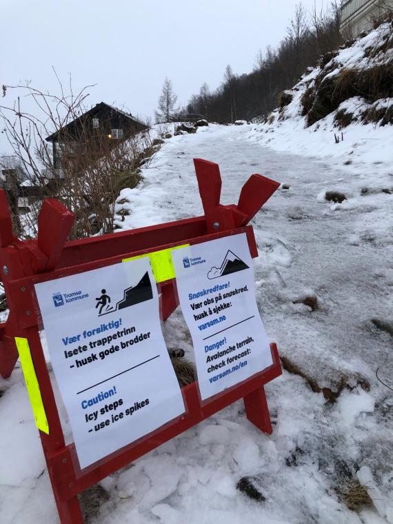 Varselskilt ved starten av turstien opp til Fjellheisen. Skiltet advarer mot svært glatte forhold. Fotografert i januar 2021.