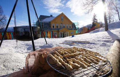 Grilling av pinnebrød uten for barnehagen en solrik vinterdag