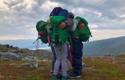 Tre barn holder rundt hverandre på en fjelltopp en tidlig høstdag