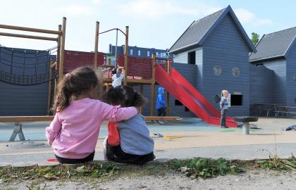 To jenter holder rundt hverandre i uteområdet ved Strandkanten FUS barnehage