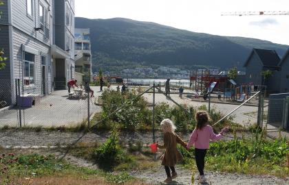 To jenter holder hender og leker i uteområdet i Strandkanten FUS barnehage