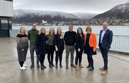 Representanter fra Visit Tromsø-Region og Tromsø kommune står på kaia med ishavskatedralen i bakgrunnen.