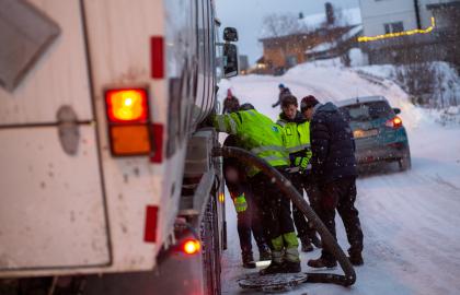 Fire arbeidere står over åpen kum midt i gate i Tromsø.