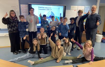 Elevene i 5. klasse på Prestvannet skole smiler og viser tommel opp. Poserer sammen med lærere og kommunetopper.